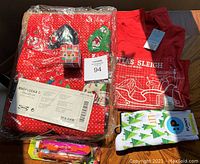 Photo of entire lot including Ikea brand advent calendar in original plastic packaging with red fabric and festive prints, red men's Christmas socks, red youth Christmas T-shirt, and two small toys in original blister packaging.