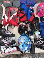 Wide shot of all sports equipment laid out including life jackets, skates, helmets, and cleats.