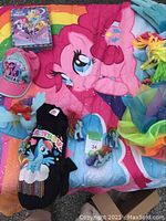 Photo of My Little Pony duvet cover, rainbow-themed items, pink hat, blue hat, black shirt, and small toys.