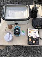 Photo showing the tabletop oven, blender motor base, sandwich press, coffee grinder, and chopper parts all on a table.
