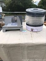 Electric food slicer and Salton Pro food dehydrator on table outdoors.