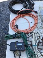 Lot overview showing various coiled extension cords and the digital outdoor timer with display and buttons.