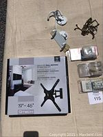 Full view of new TV wall mount box, assorted metal coat hooks and plastic cable clamps on surface.