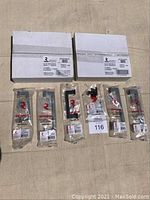 Wide view showing 9 pieces of Richelieu door/drawer hardware including two unopened boxes, one opened box, and six sealed hardware bags with mounting screws.