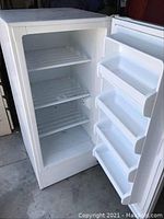 Interior view showing three white-coated wire shelves and three door bins