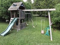 Full view of wooden play structure showing slide, swings and overall layout