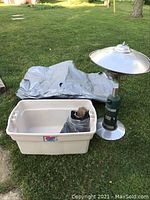 Patio heater, large white plastic tote, and tarp laid on grass outside