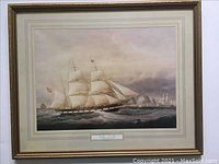 Full view of framed maritime print showing ship on ocean with sails up and shore in background