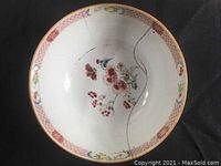 Top view of bowl showing floral pattern in center and decorative border with repaired cracks.