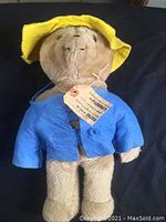 Vintage Paddington Bear plush about 18 inches tall wearing original blue jacket and yellow hat.
