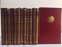 Front view of 12 red leather-bound volumes plus one volume or slipcase with gilt emblem