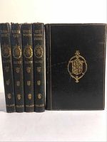 Front and spines of five leather-bound books by Sir Walter Scott showing gold embossed text and crests