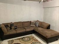 Full sectional couch in corner showing two-piece design, microsuede cushions, faux leather base, and throw pillows