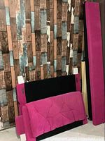 Photo showing the disassembled hot pink upholstered single bed frame parts against a wood plank patterned wall background.