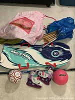 Photo showing the kids play tent fabric and wooden poles, snow glider, ice skates, and balls arranged on floor