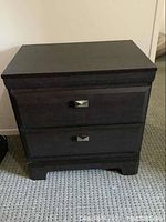 Front view of the nightstand showing two drawers with metal handles and dark finish.