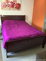 Front view of queen sleigh bed frame showing headboard with curved sleigh design, purple bedspread on mattress (not included).
