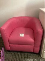 Pink kids leatherette armchair with minor paint chip wear on left armrest shown from front.