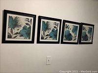 Four framed floral pictures with teal and blue flowers, black frames, hanging in a row on a wall.
