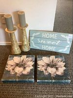 Full lot showing two candlesticks with candles, wooden Home Sweet Home sign, and two square floral canvas pictures