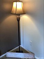 Full view of the lamp standing in a corner with the wooden sign placed at the base