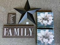 Photo of the Family sign, metal star, and three canvas pictures arranged on carpet.