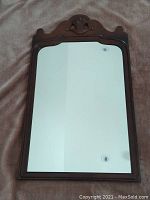 Full view of the antique wall mirror showing the entire rectangular reflective glass area and brown wooden frame with curved and carved details