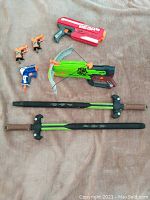 Wide shot of all included Nerf blasters and foam swords on a neutral background.