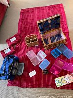 Full picnic lot arranged on red striped tablecloth with basket, cooler bag, containers, and accessories