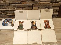 Five Gone with the Wind collector plates, four in original boxes and one without box, arranged on a wood surface against a stone wall.