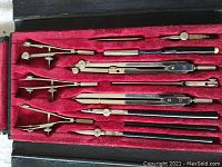 Top view of the 12 piece drafting/engineering instruments arranged inside red velvet lined case.