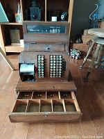 Overall front view showing wooden housing, keys, display and open drawer.