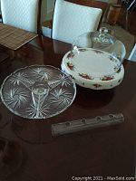 Clear 12 inch glass cake pedestal with pinwheel starburst design, 13 inch Royal Albert Old Country Roses plate and 10 inch glass dome on table