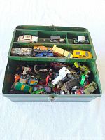 Green metal tackle box open with over 50 assorted diecast cars inside, cars are mixed and vary in size and color.