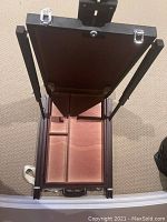 Open view showing internal storage compartments lined for paint organization inside the foldable easel case.