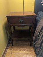 Single wooden bedside table against yellow wall with a drawer and lower shelf, showing total size and finish.