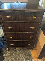 Front view of an antique walnut chest of drawers with four drawers, each with unique Bakelite-like handles.
