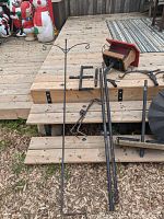 Overview of long metal pole with hanging hooks, parts on wooden deck and ground