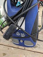 Front view of AR Blue Clean 383 pressure washer showing blue body with black handle, electrical cord, and hose coiled around unit