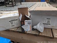 Photo showing two white Cardboard boxes labeled 'Standard 66300' with one open box of 6 LED bulbs, one bulb outside the box.