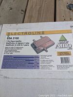 Box label showing brand Electroline, model EDA 2100, product description '1 Port Signal Amplifier', compatibility with cable TV, and multilingual text with warranty information.