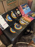 Photo of vinyl records in sleeves with disco style RCA labels and colorful designs, arranged on a black surface.