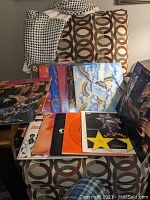 Seventeen assorted disco vinyl records displayed on a chair with colorful album covers visible, showing variety of LPs and singles.