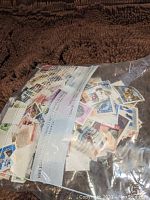 Clear plastic bag filled with assorted used postage stamps from various countries visible through the bag.