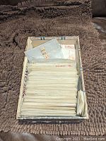 Top-down view of open dealer box filled with stacked translucent paper envelopes containing stamps