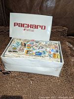 White Packard Foam Treads shoebox filled with mixed used stamps photographed open showing the variety of stamps inside.