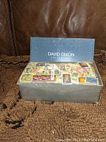 Shoe box labeled David Dixon Collection containing numerous postage stamps with varied designs on top.