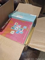 Cardboard box partially open revealing a red World Stamp Album and another box inside the larger container.