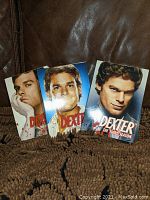 Photo of three Dexter DVD sets in used condition showing the front cover artwork for Seasons 1, 2, and 3.