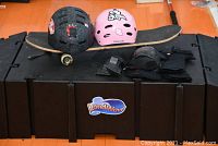 Photo of 3-piece black LandWave skateboarding ramp with two helmets, skateboards, and knee pads placed on top